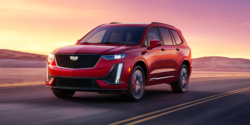 A red XT6 drives on a deserted road at sunset, showcasing sleek lines and dynamic design against a vibrant sky, conveying a sense of adventure.