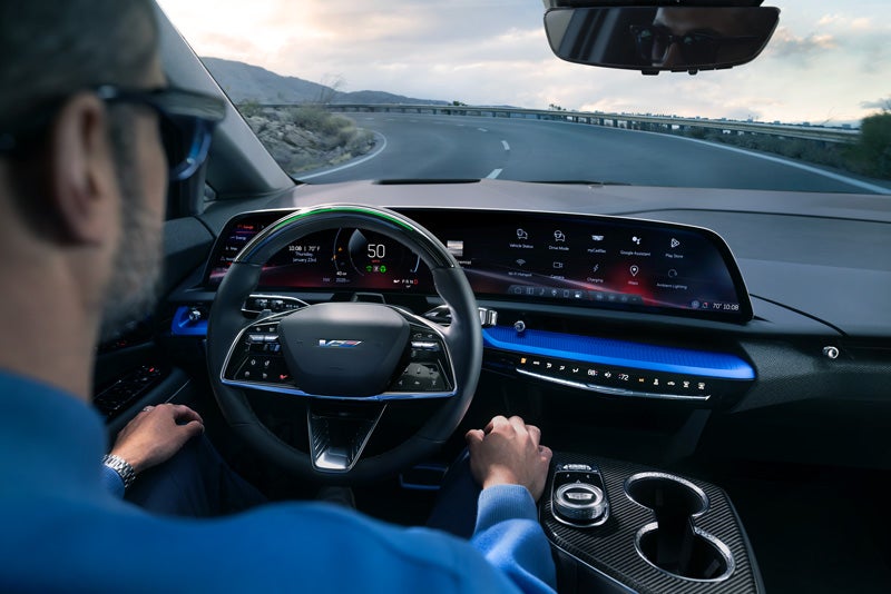 Front View of the 2026 OPTIQ-V Driving Through the Dusk Utilizing its Headlights | AutoNation Cadillac Corpus Christi in Corpus Christi TX