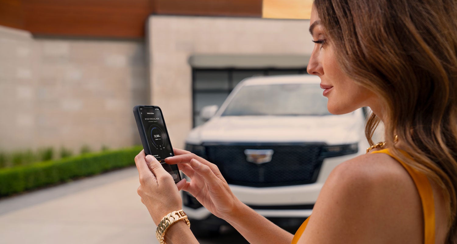 lady checking her mobile with a Cadillac vehicle background | AutoNation Cadillac Corpus Christi in Corpus Christi TX